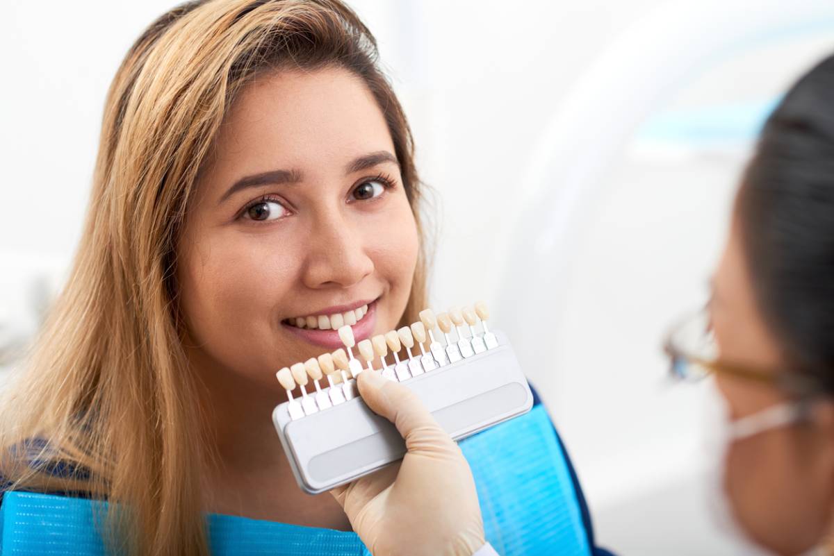 A woman smiles brightly while holding a toothbrush, showcasing her enthusiasm for dental hygiene.