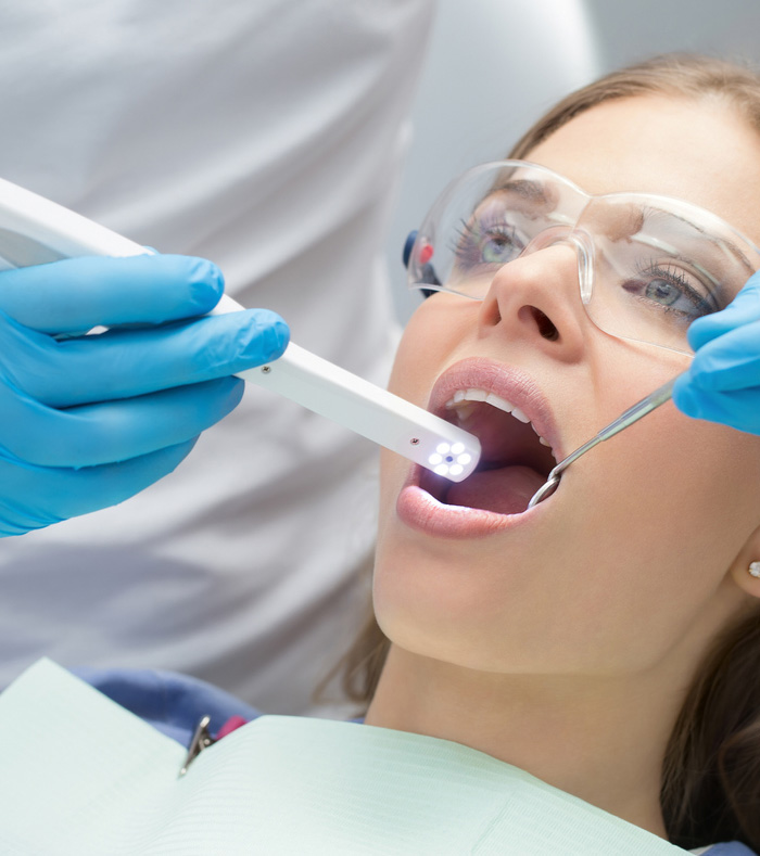 A woman receiving a dental cleaning from a dentist in a clinical setting, showcasing oral hygiene practices.