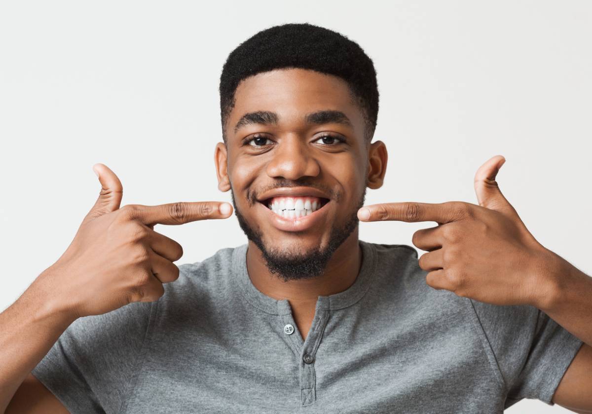 A man smiling and giving a thumbs up sign with both hands, expressing positivity and approval.