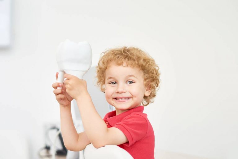 A young boy proudly holds up a toothbrush, showcasing his enthusiasm for dental hygiene and personal care.