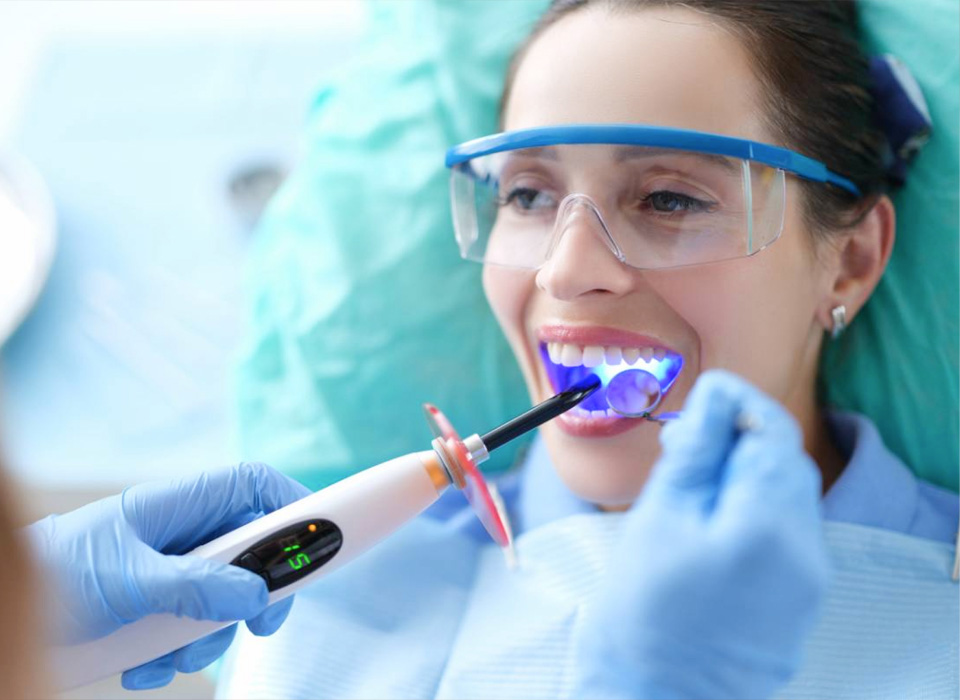 A woman receives a dental cleaning as she brushes her teeth with a toothbrush, promoting oral hygiene and health.