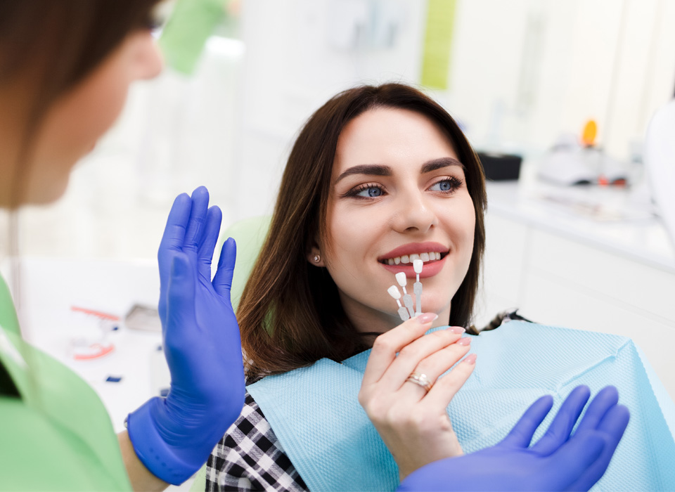 A woman sits in a dental chair as a dentist cleans her teeth, ensuring her oral health and hygiene.