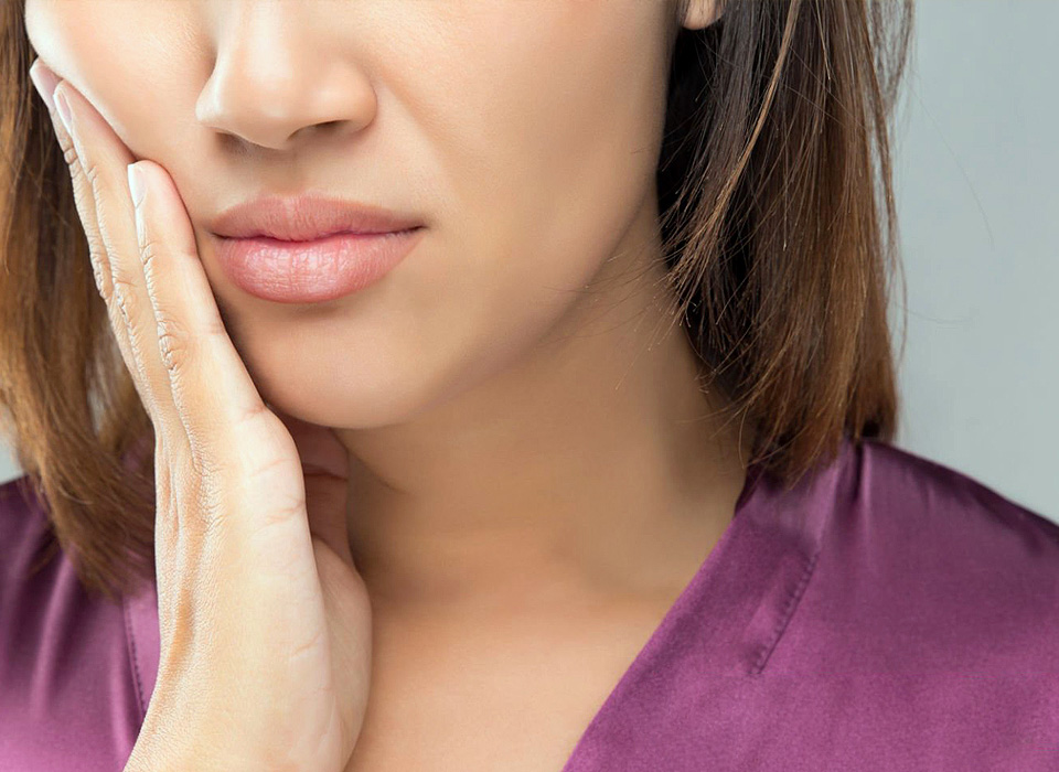 A thoughtful woman resting her chin on her hand, reflecting in a serene environment.