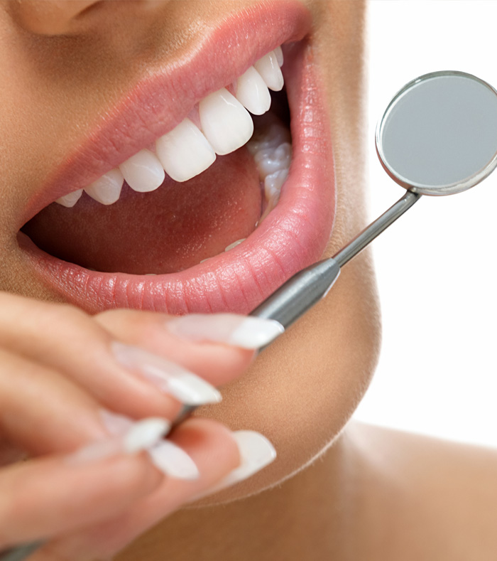 A woman is brushing her teeth with a toothbrush, focusing on her dental hygiene in a bright bathroom setting.