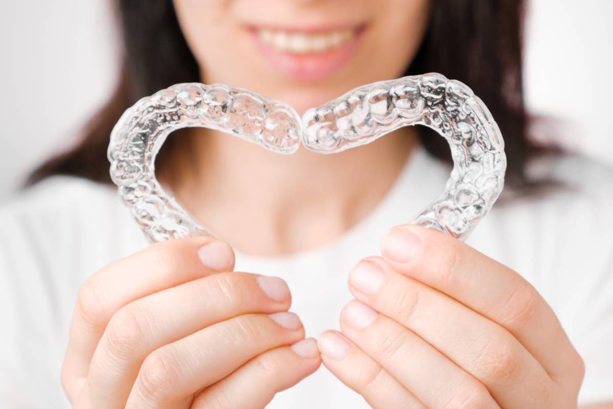 A woman is holding a heart-shaped Invisalign, symbolizing love and affection in a vibrant setting.