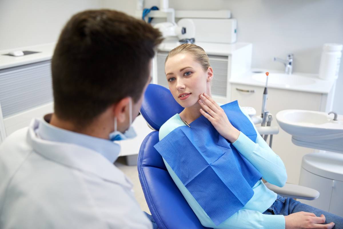 A woman converses with a man while seated in a dental chair, indicating a dental consultation or discussion.