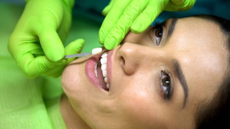 A woman sits in a dental chair while a dentist cleans her teeth, showcasing a routine dental check-up.